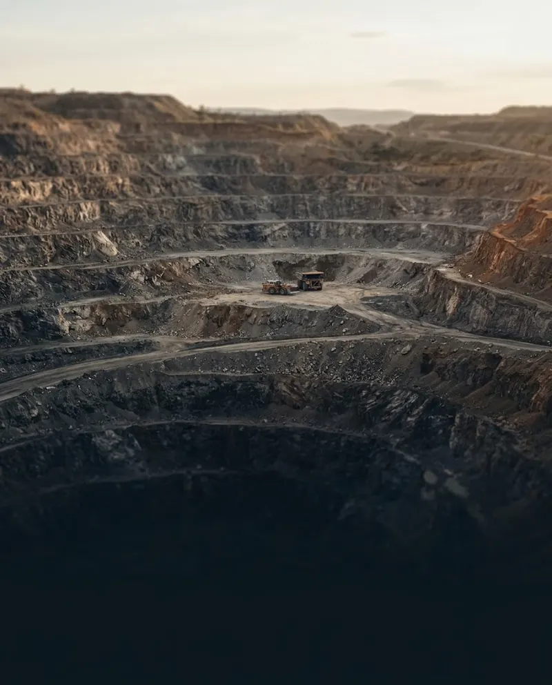 Terraced open-pit mine with haul trucks at dusk