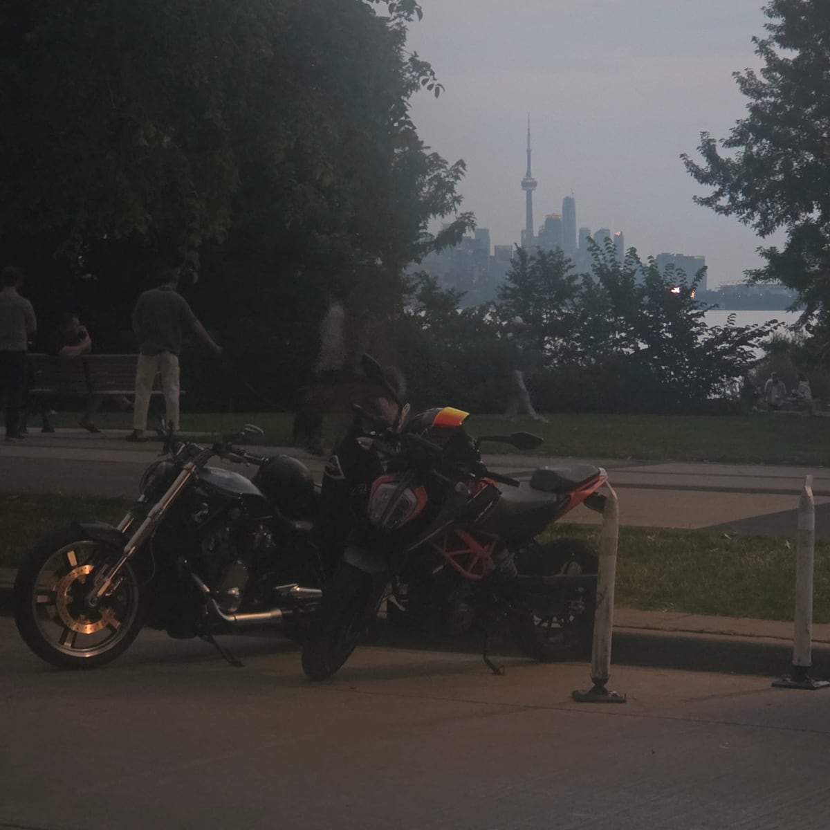Motorcycles parked at the Toronto waterfront at dusk, CN Tower skyline in background